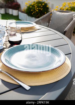 table setting on an outdoor terrace in summer with two empty plates and two glasses of wine, ready to be served Stock Photo