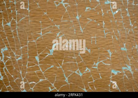 Abstract image, light reflecting on cracked and broken glass with a light coloured wood behind. Stock Photo