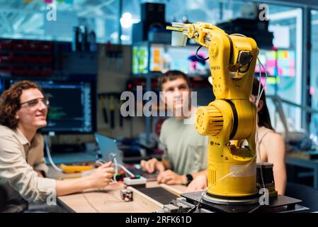 Group of young people doing experiments in robotics in a laboratory. Robot and tools on the table Stock Photo