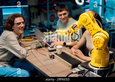 Group of young people doing experiments in robotics in a laboratory. Robot and tools on the table Stock Photo