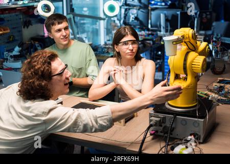 Group of young people doing experiments in robotics in a laboratory. Robot and tools on the table Stock Photo