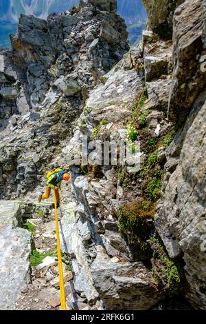 Man alpinist rappelling on steep rock in Swiss Alps Stock Photo
