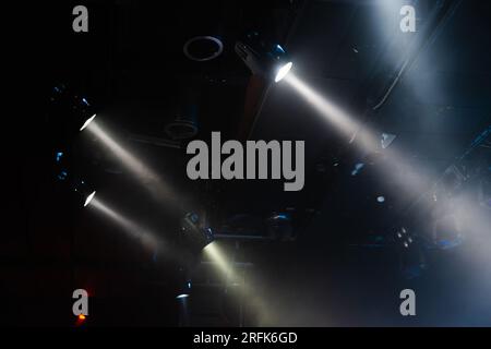 Beams of stage spotlights in smoke over dark background, modern stage illumination equipment Stock Photo