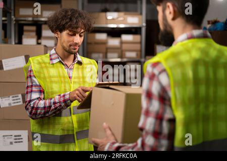 Two middle eastern warehouse workers using a digital tablet does inventory. Logistics employees working with warehouse management software. Stock Photo