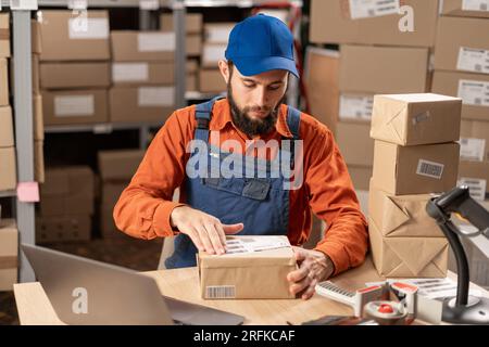 Warehouse worker applying shipping label on parcel boxes Stock Photo