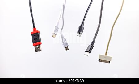 USB type A and C as well as Micro USB and Lightning plug with cable exposed in front of white Stock Photo