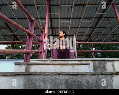 Oct.14th 2022 Uttarakhand, India. Young Indian man sitting alone on stadium stands in Dehradun City, India. Contemplating solitude in the empty arena. Stock Photo