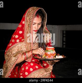 Oct.14th 2022 Uttarakhand, India.Cultural celebration: Indian married woman performing Karwachauth pooja ritual in traditional attire. Embracing Hindu Stock Photo