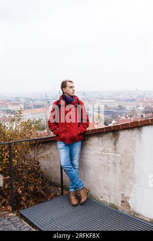 man in red jacket and blue jeans walks on streets of autumn Praga Stock Photo