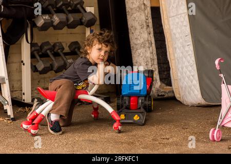 toddler boy sitting on toy outside Stock Photo