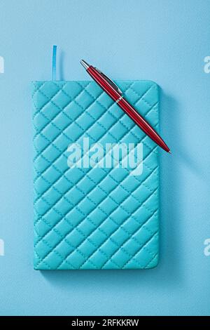 Blue Notepad And Red Ballpoint Pen On Blue Background Stock Photo