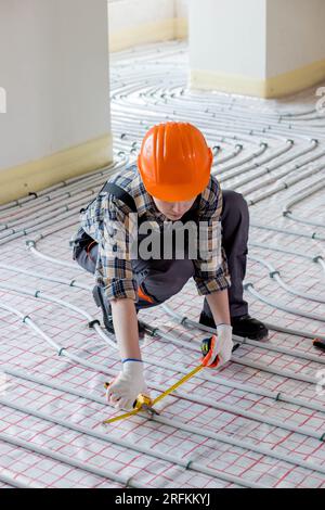 Woman worker takes measurements during the installation of a warm floor. Warm floor heating system. Stock Photo