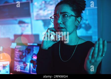 Night, angry and a woman hacker on a phone call during a cyber security emergency in her office. Communication, software problem and dark with a Stock Photo