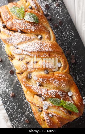 Soft homemade braided sweet bread with chocolate and custard close-up on a slate board on the table. Vertical top view from above Stock Photo