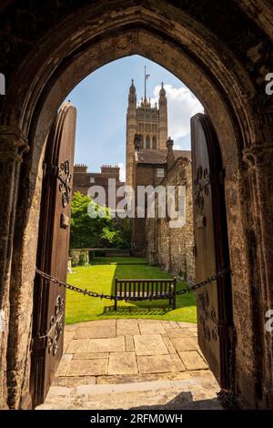 Looking through old medieval wooden doors and archway into a historic brick courtyard with the Palace of Westminster, UK Parliament's Victoria Tower. Stock Photo