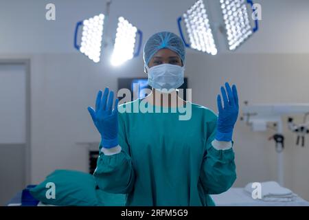 Portrait of african american female surgeon wearing surgical gown in operating theatre at hospital Stock Photo