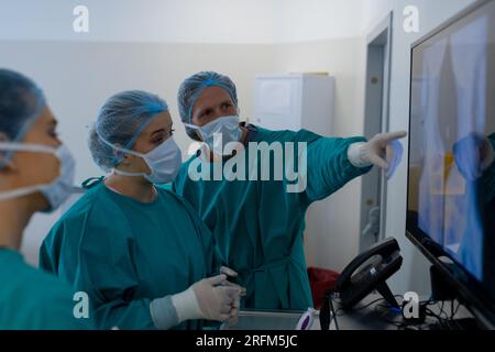Diverse surgeons looking at x-ray scans in operating theatre at hospital Stock Photo