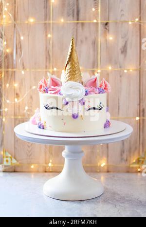 Gorgeous unicorn cake with golden waffle horn, eyelashes and cream cheese frosting on festive background Stock Photo