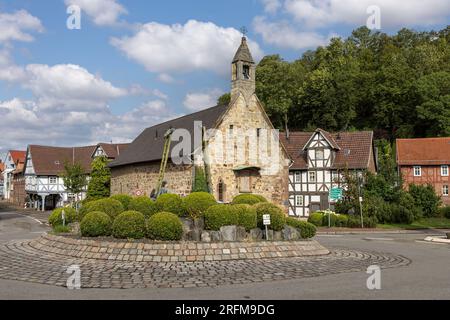 Hospital chapel of the Holy Ghost and fountain sculpture 'Der Brunnen der Verwunschenen' by Carin Grudda on roundabout in town Gudensberg, Germany Stock Photo