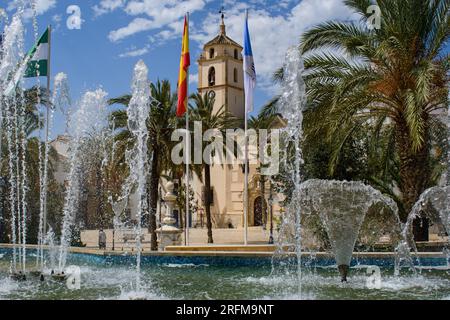 Albox, Almeria, Spain. The early 18c.parish church (Iglesia de Santa María)  seen through fountains playing in the Plaza de Pueblo. Stock Photo