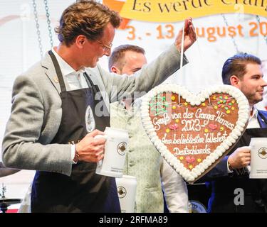 Herne, Germany. 04th August, 2023. Prime Minister of North Rhine-Westphalia, Hendrik Wüst (CDU) is given a gingerbread heart whilst in the festive tent to officially open the Cranger Kirmes fairground in Herne. Cranger Kirmes funfair is one of the largest in Germany. Pop singer Michelle and others perform. The popular fair regularly attracts more than 4m visitors during its 10 day run. The fair dates back to the early 18th century at Crange. Credit: Imageplotter/Alamy Live News Stock Photo
