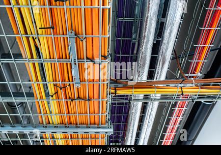 Electrical conduits system and metal pipeline installed on building ceiling, color cables, power house concept Stock Photo