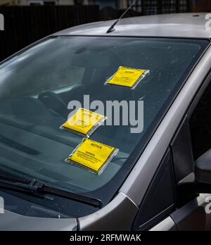 Multiple Parking Tickets or Penalty Charge Notices on the windscreen of a car parked in the street Stock Photo