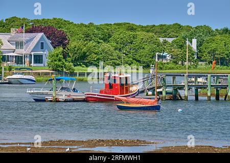 A cute little Red Tug boat,The Daisy Mae, at a dock or pier on Lewis Bay inlet in Cape Cod,Massachusetts.USA. Near Hyannis Harbor. Stock Photo