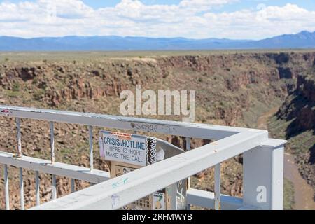 Crisis hotline call box on railing to Rio Grande Gorge Bridge high above Rio Grande river on US 64 with Sangre de Cristo Mountains on horizon Stock Photo