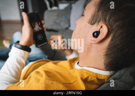 young beautiful man is watching a movie on her smartphone. Viewing video clips on Internet by guy. listen music with phone. Stock Photo