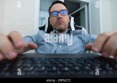 Male hands or men office worker typing on the keyboard. Programmer at work. A professional with glasses looks at the monitor Stock Photo