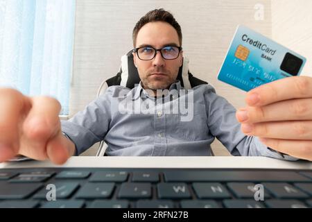 Young businessman holding a credit card and typing. On-line shopping on the internet using a laptop. man enters the card details on the website Stock Photo