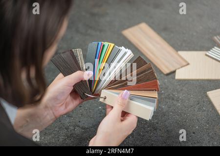 The designer chooses samples of pvc edging for the production of kitchen furniture from LMDP. Close-up woman's hands hold samples of various colors of Stock Photo