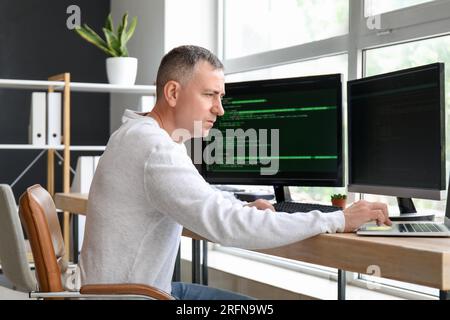 Mature male programmer working in light office Stock Photo