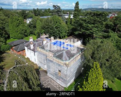 Roof repairs using tarpaulin covers to protect the building property in UK taken in July 2023 Stock Photo
