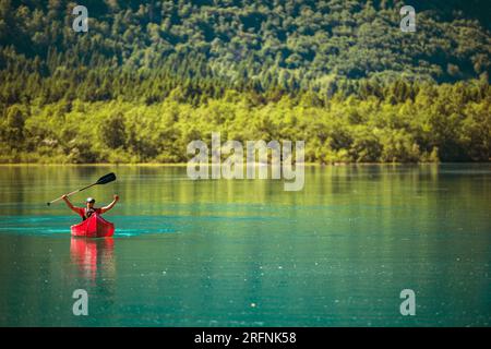 Happy Traveler Inside Red Canoe on a Glacial Lake with His Hands Up Stock Photo