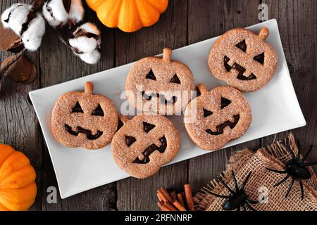 Plate of Halloween Jack o Lantern cookies. Chocolate and pumpkin spice. Above view with decor on a dark wood background. Stock Photo