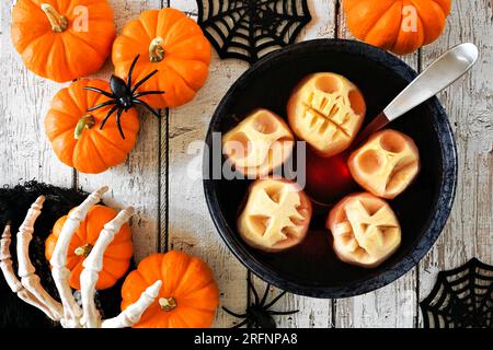 Spooky Halloween apple head punch. Overhead table scene on a white wood background. Stock Photo
