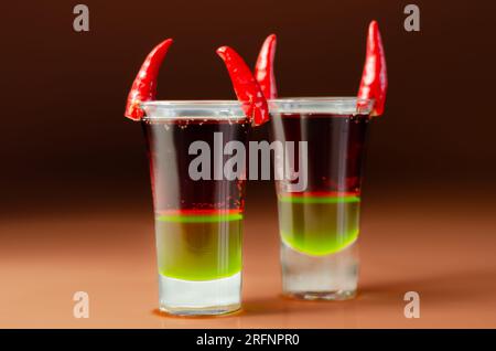 Layered drink shot prepared with vodka, green liquor, grenadine and ...