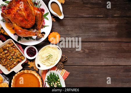Classic Thanksgiving turkey dinner. Top down view side border on a dark wood background with copy space. Turkey, mashed potatoes, stuffing, pumpkin pi Stock Photo