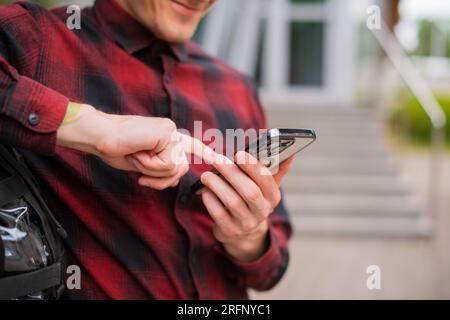 Close-up casual man using a modern smartphone while walking along the city street in the city outdoors, Lifestyle and technology, Business on the go Stock Photo