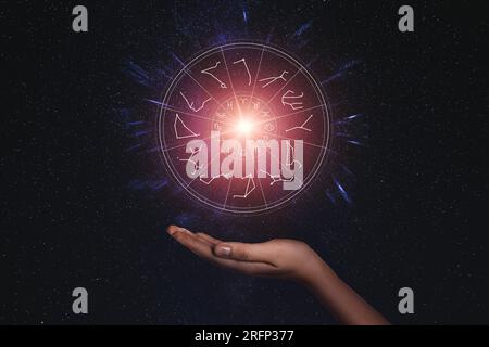 Woman holding illustration of bright star with zodiac wheel around it in open space, closeup Stock Photo