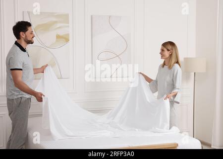 Couple changing bed linens in room. Domestic chores Stock Photo