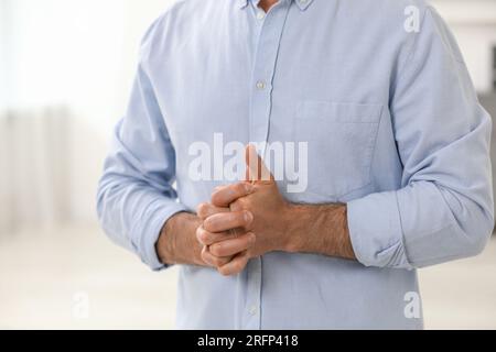 Man cracking his knuckles on blurred background, closeup. Bad habit Stock Photo