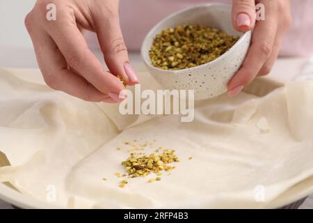 Woman putting filling into baking dish with dough to prepare baklava, closeup Stock Photo