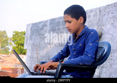 Teen handsome student using laptop. Cheerful boy studying online on laptop. Technology, communication, social media, day time Stock Photo