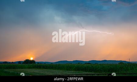 a lightning bolt cleaves the sky during a colorful sunrise Stock Photo