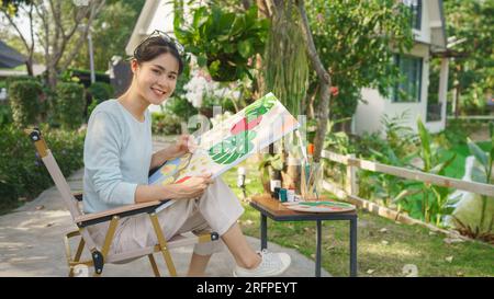 Outdoor activity concept, Female artist sits in park and painting ...