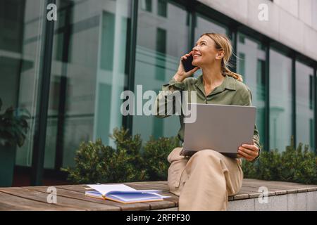 Smiling woman manager talking with client and work on modern building background Stock Photo