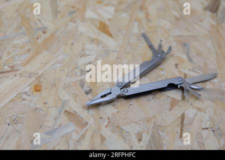 Silver all purpose pocket knife on a rustic wooden background. Top view folding knife with tools Stock Photo